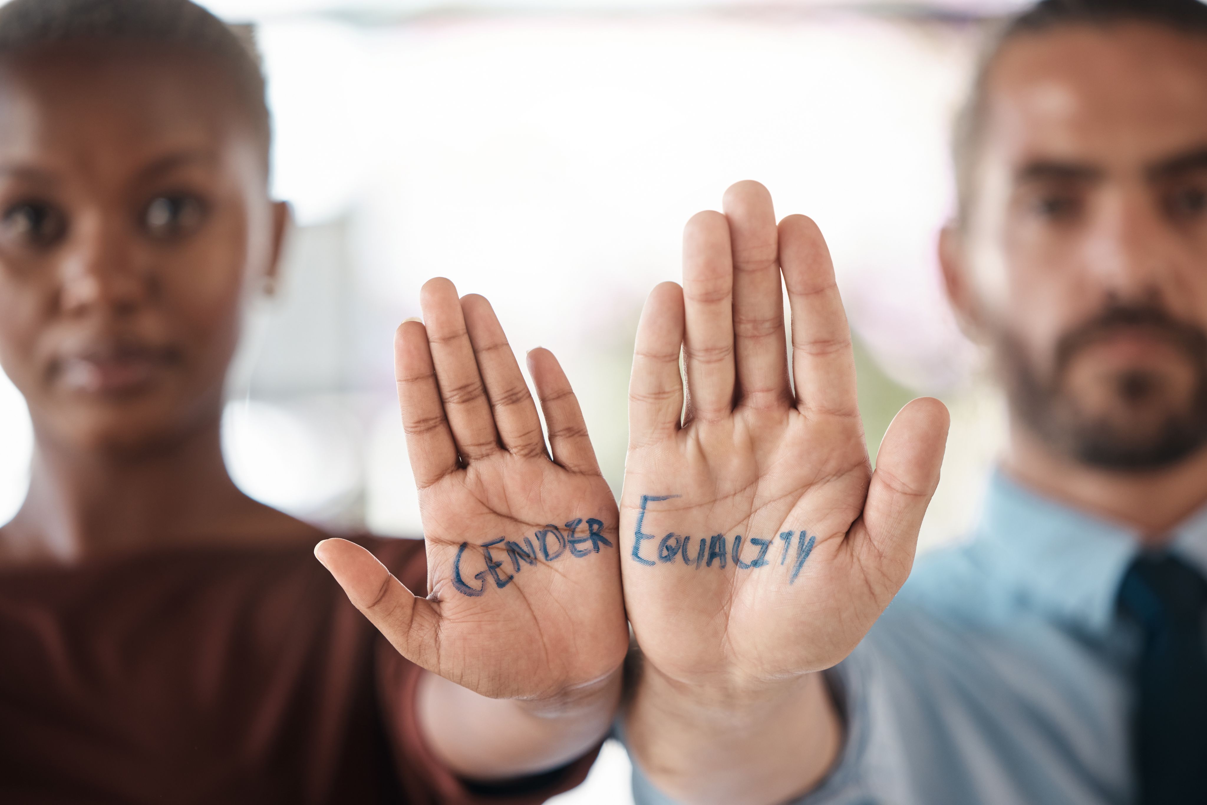 2 people holding their hands up, with the words 'Gender' and 'Equality' on them