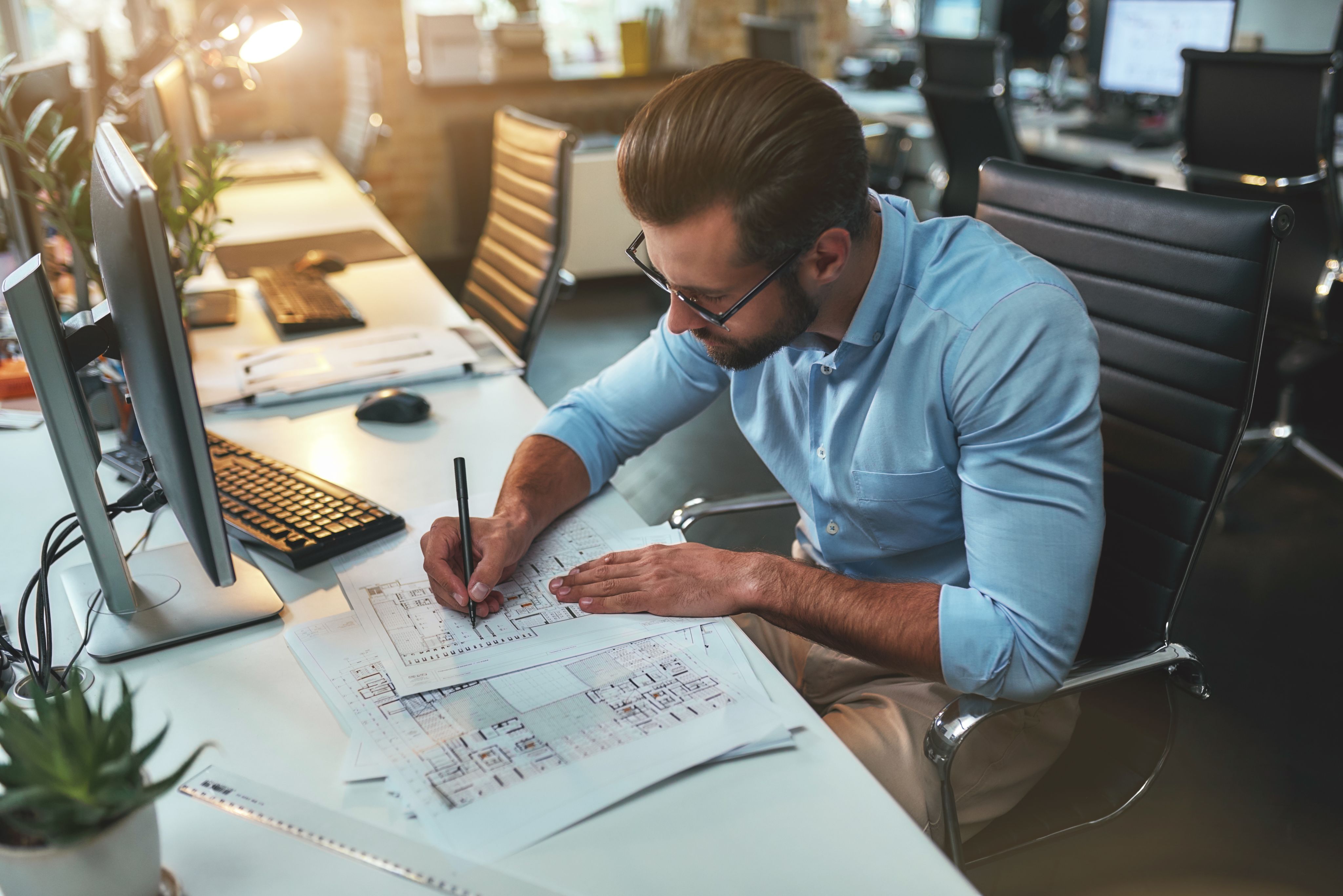 Architect works on a set of drawings at his desk - Copyright - Friends Stock / Adobe Stock