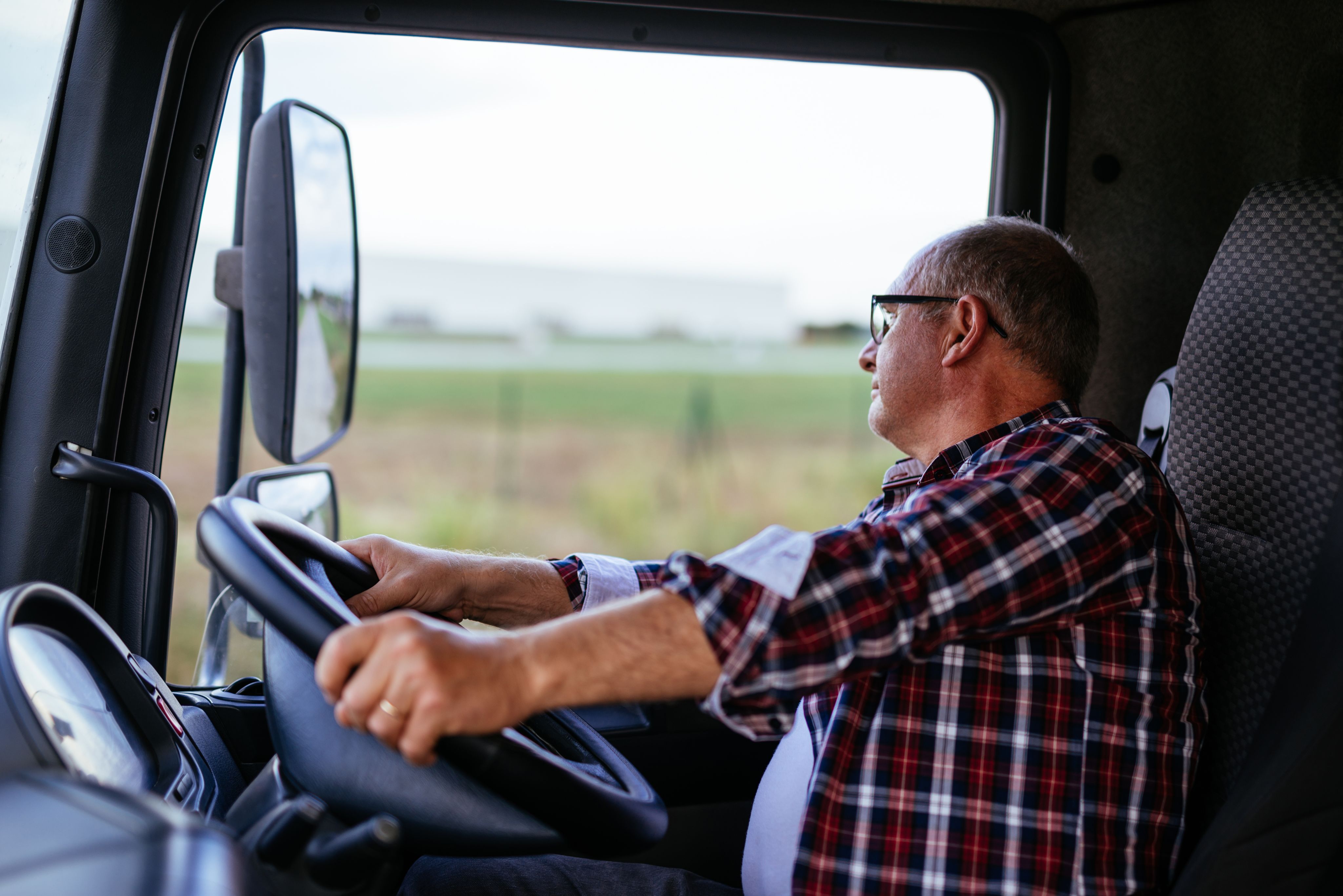 Male truck driver driving his vehicle - Copyright: bernardbodo / AdobeStock
