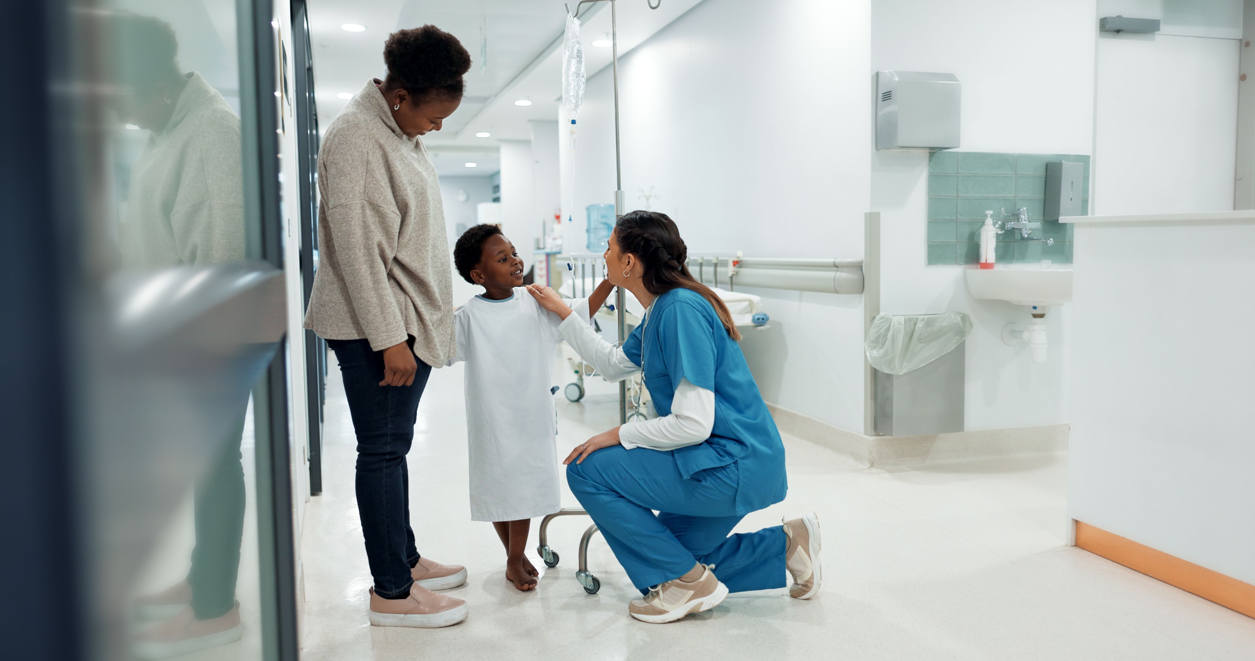 Woman pediatrician talking to a child patient and his parent in a hospital corridor - Copyright - N F/peopleimages.com / Adobe Stock
