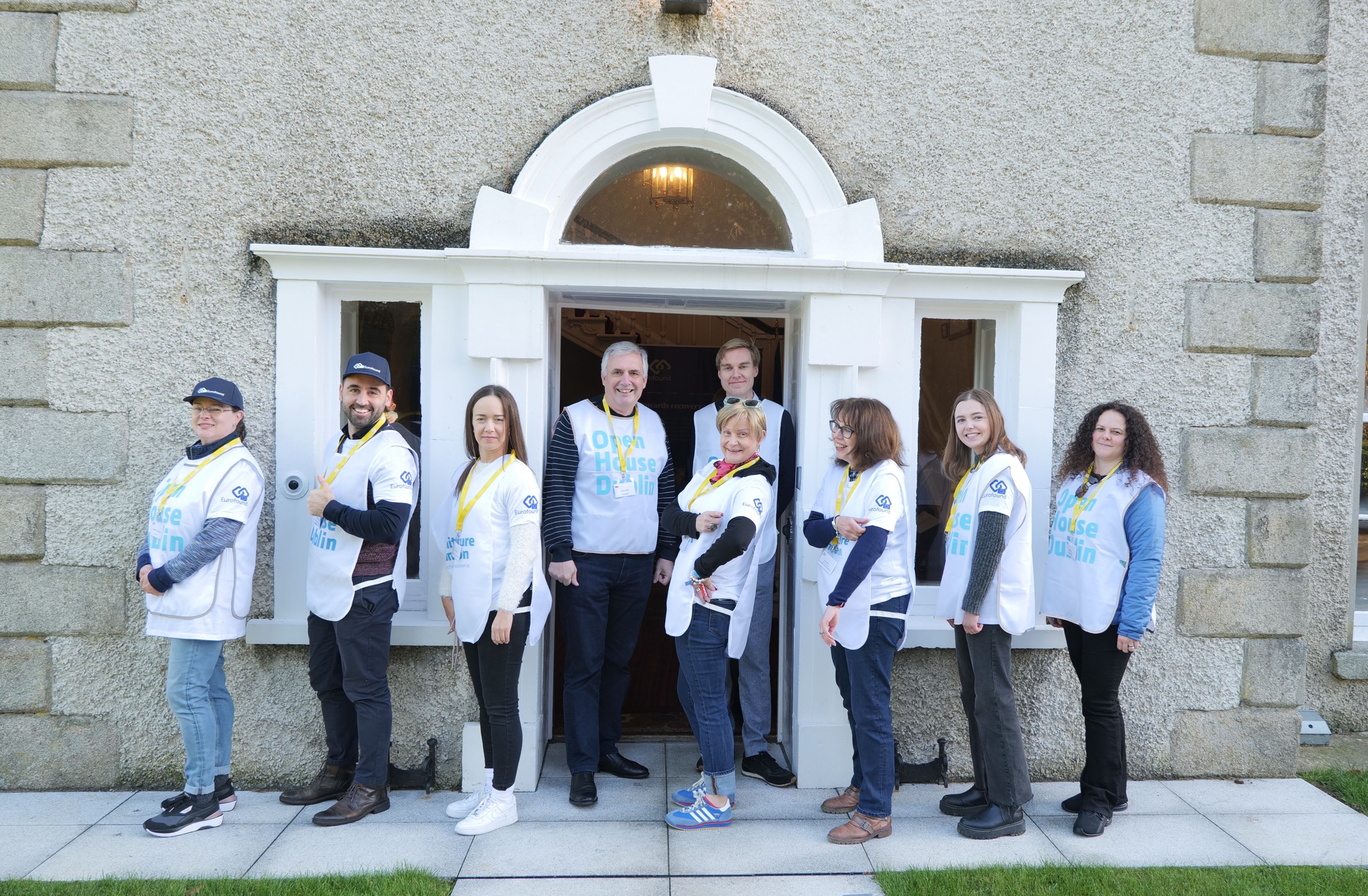 Eurofound staff members line up outside a Eurofound building wearing Open House hats and bibs