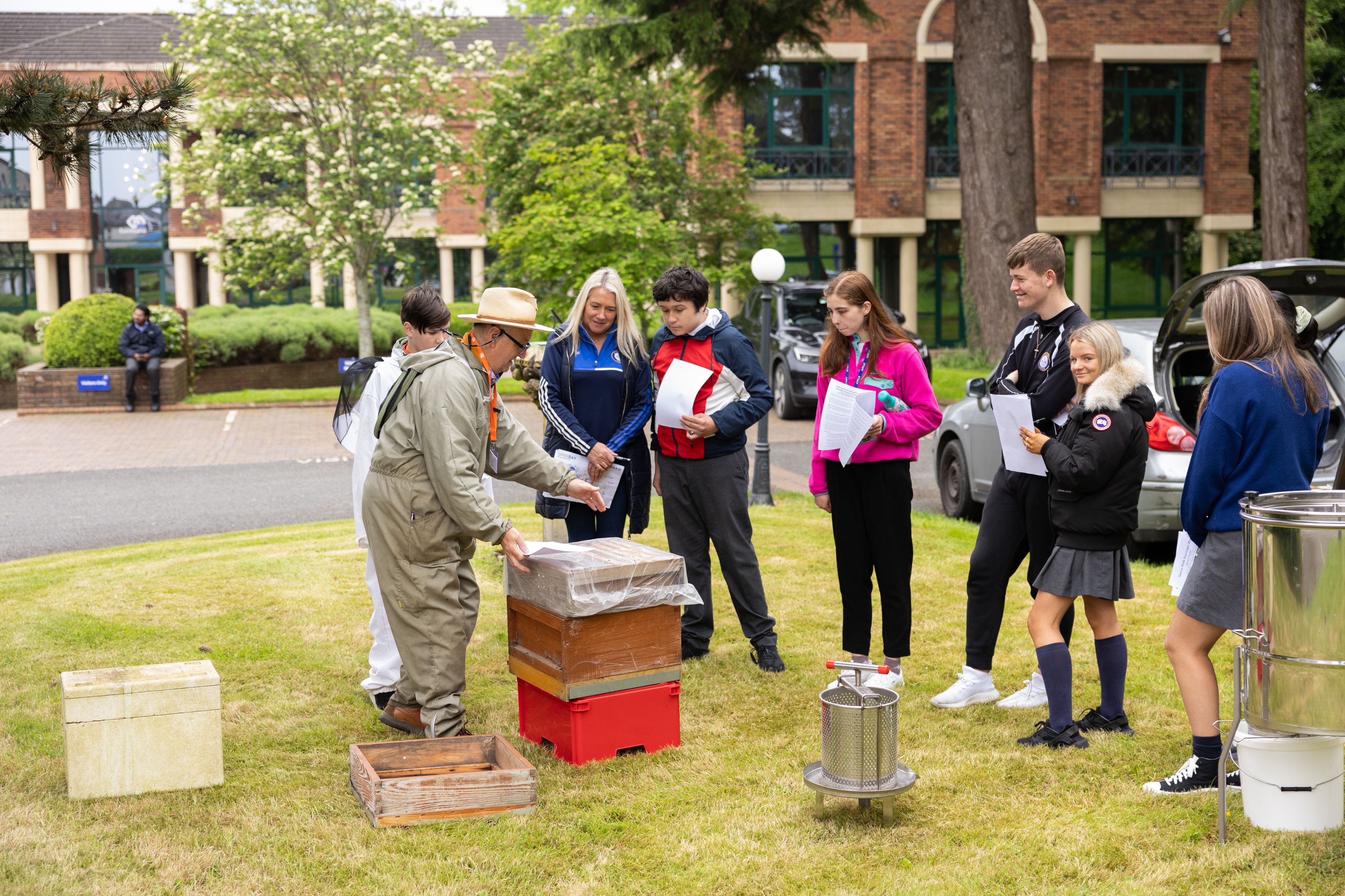Picture of a bee keeper showing how he works to a group of school children outside at Eurofound