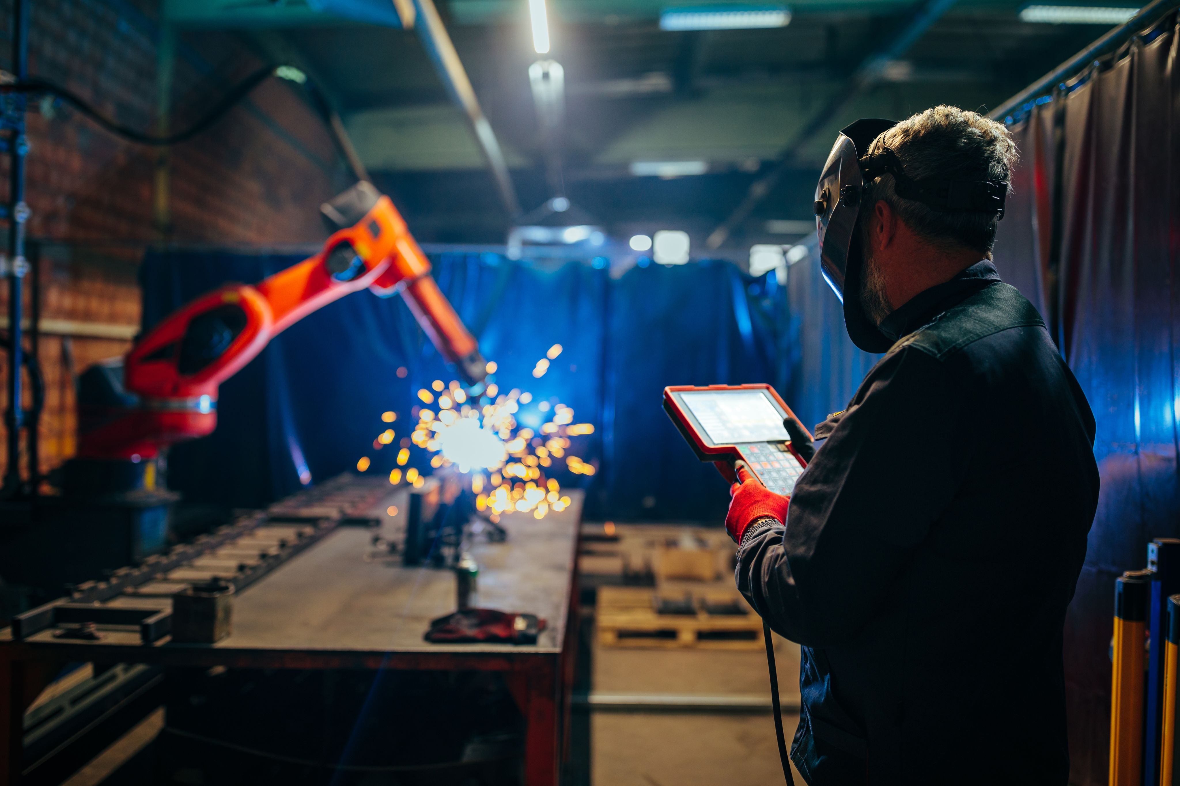 Man watching a robotic arms with a controller in his hands