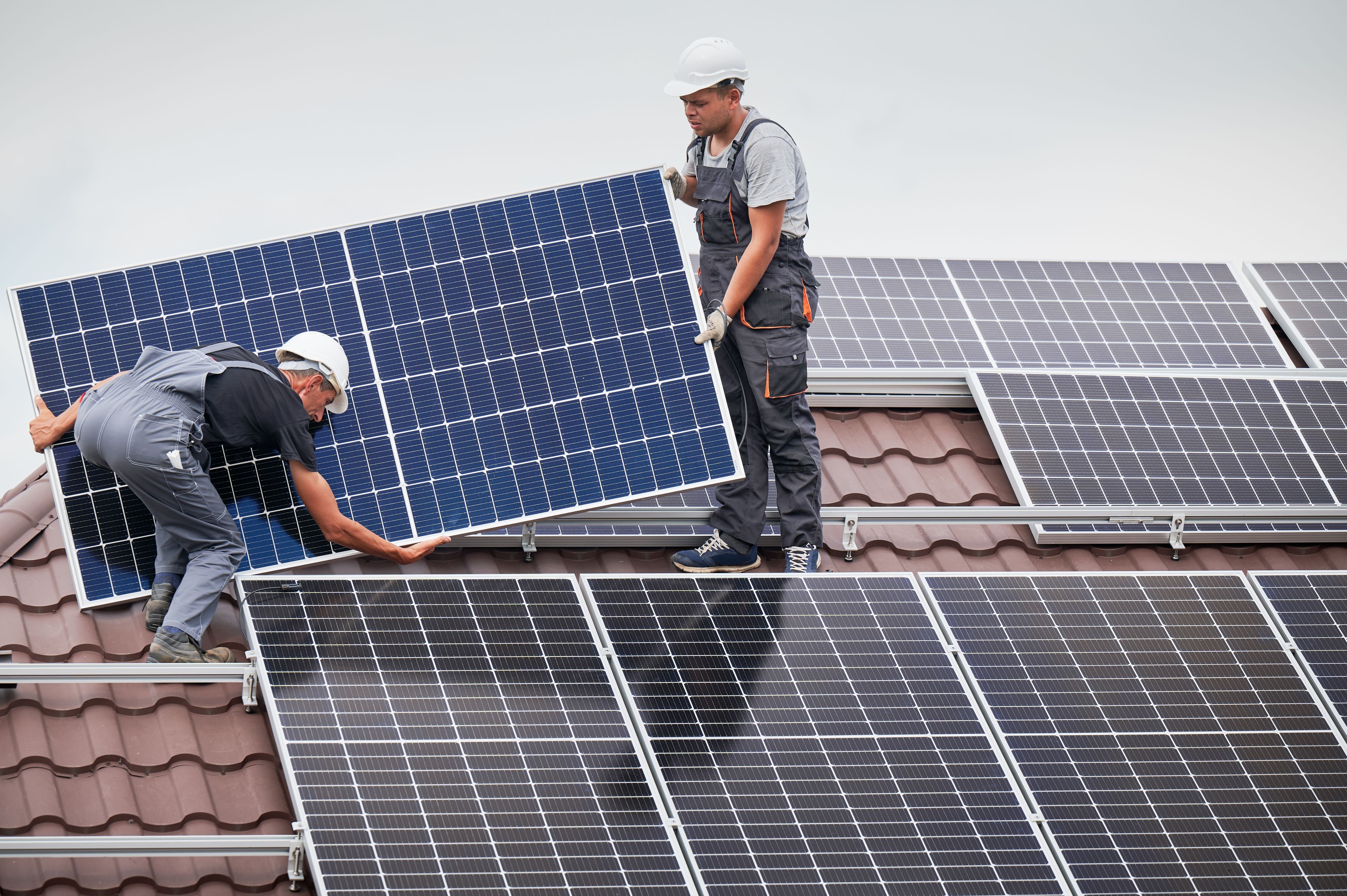 Two men installing solar panels on a roof