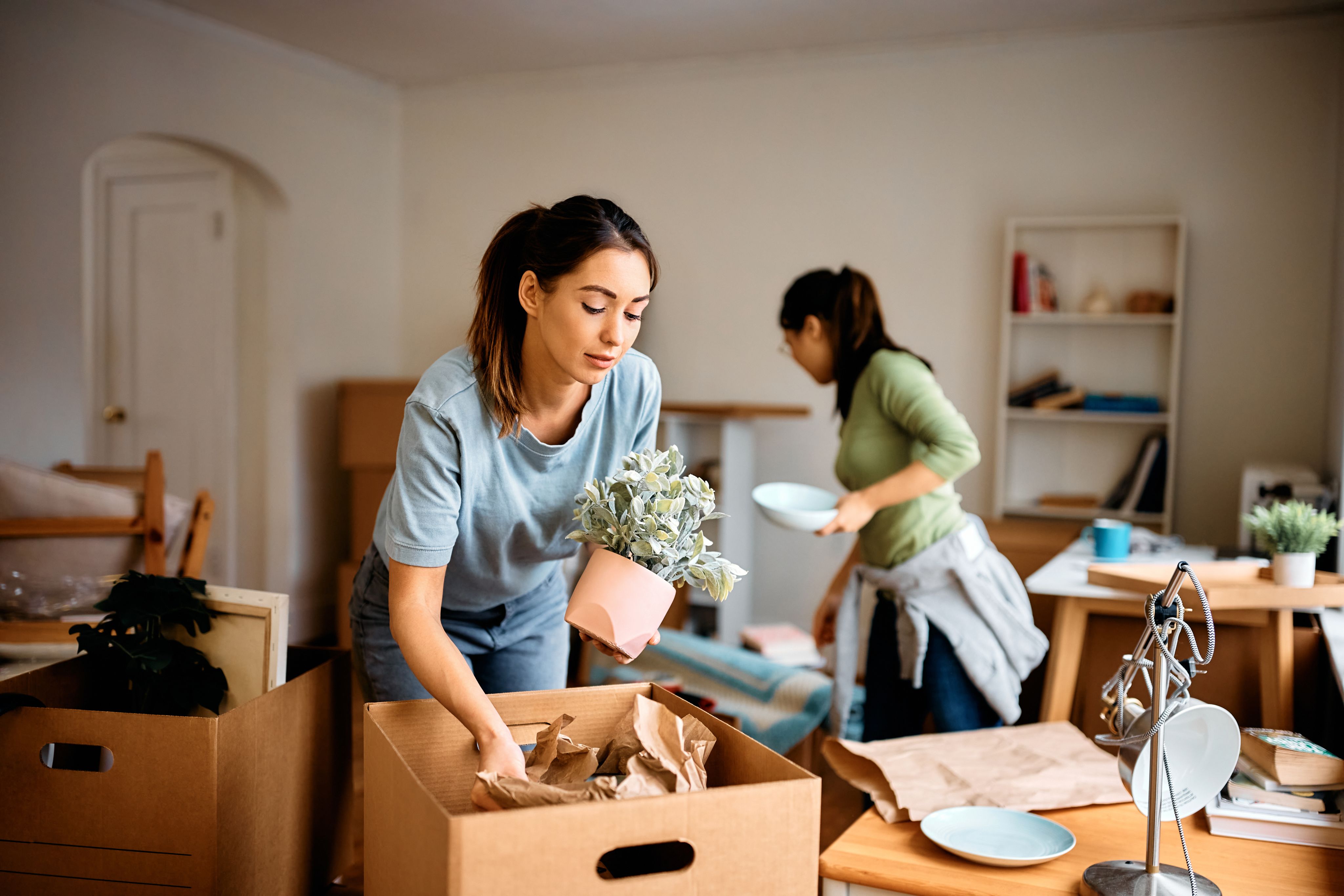 Two women unpacking boxes to move into new home