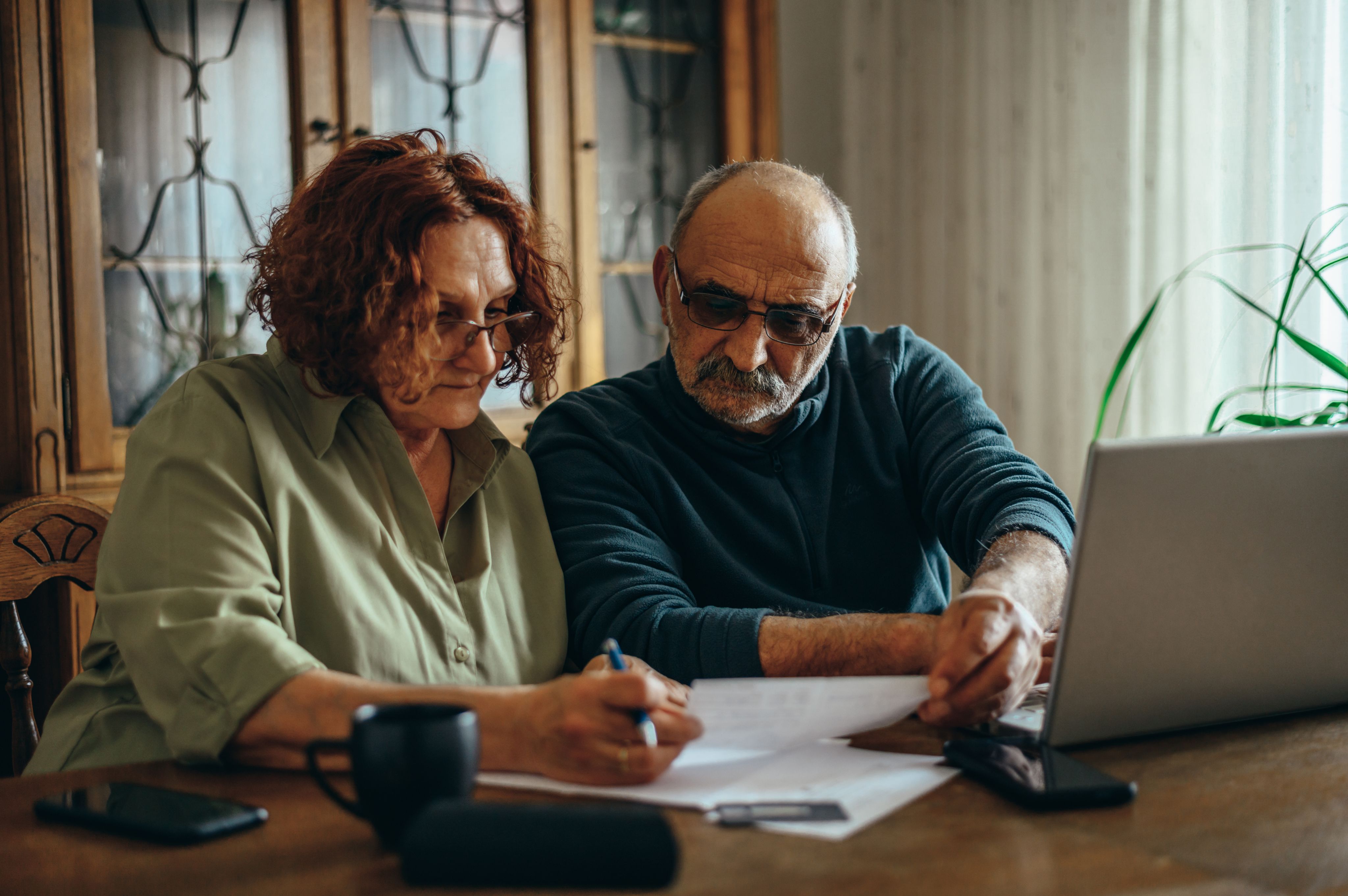 Man and woman sorting through papers in front of a laptop