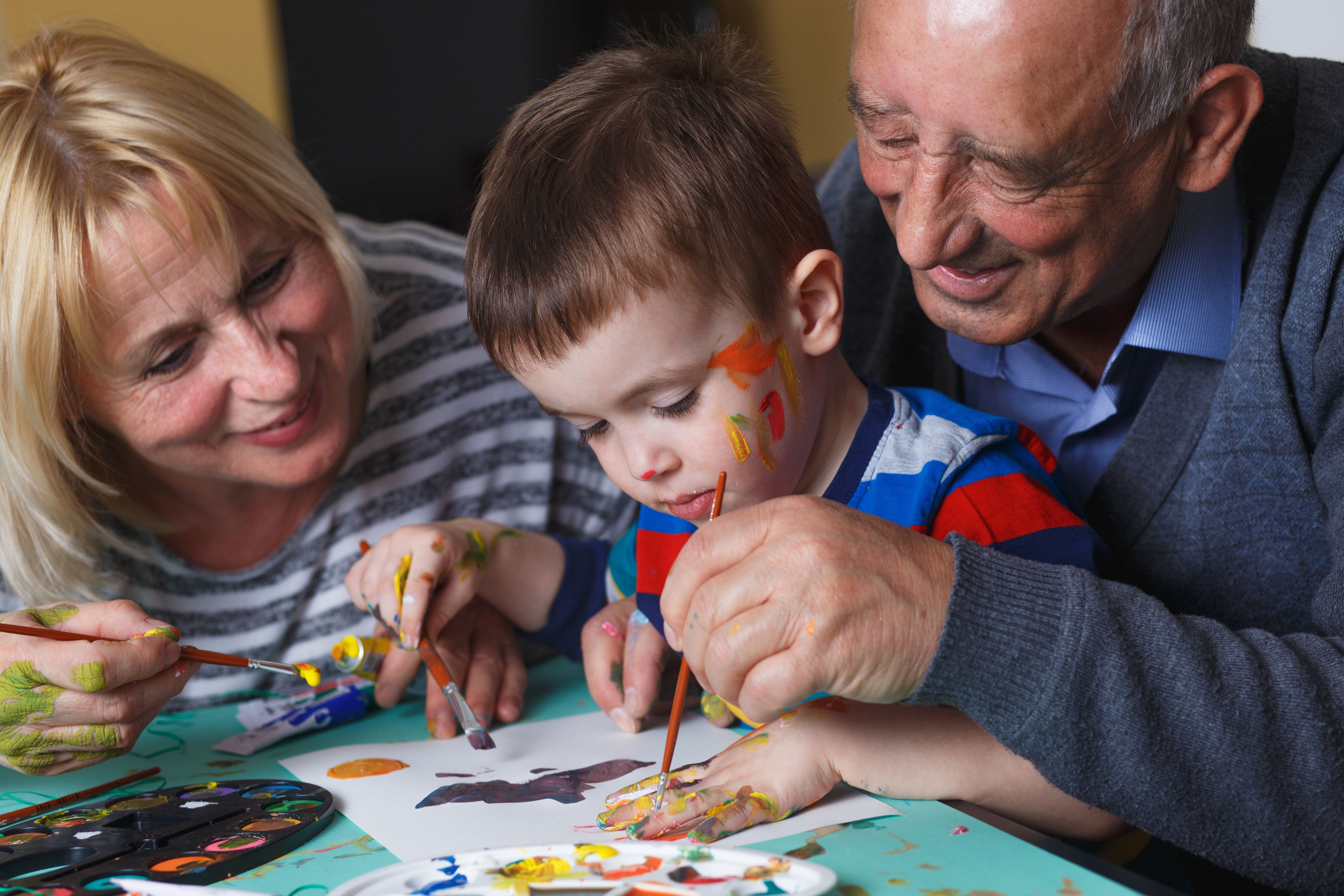 Grandparents painting with their young grandchild